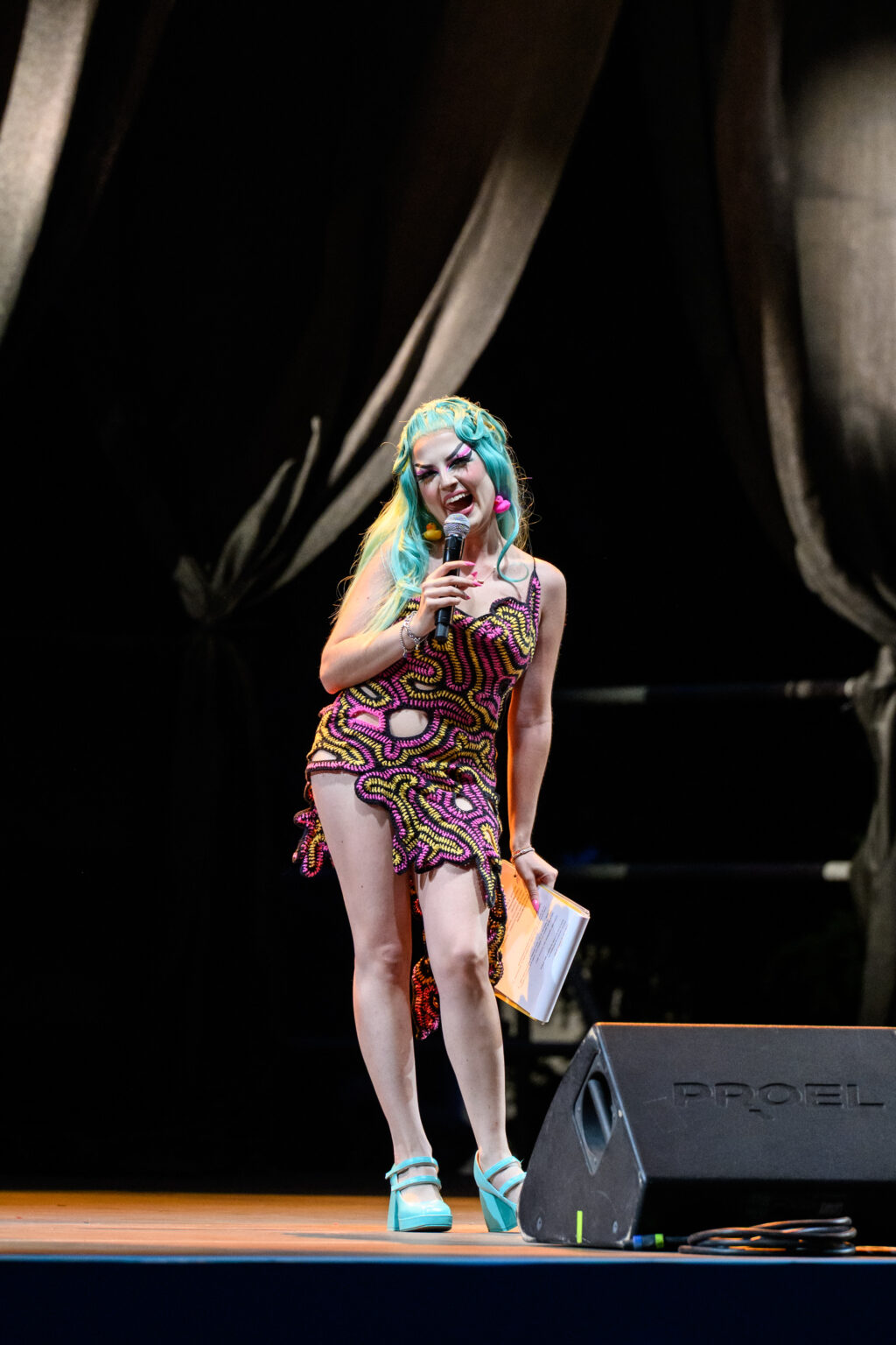 Comica sul palco di QUEER PANIC! al Castello Sforzesco, con microfono e copione in mano